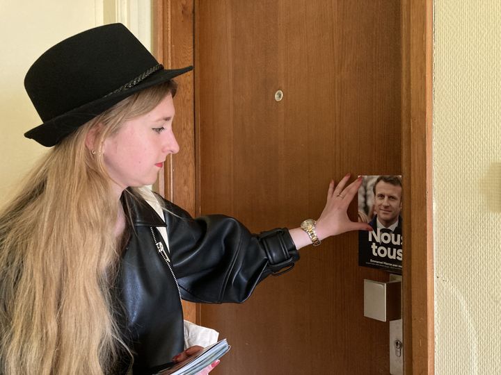 Anastasia, militante LREM, laisse un tract Emmanuel Macron sur une porte à Strasbourg, le 13 avril 2022. (MARGAUX DUGUET / FRANCEINFO)