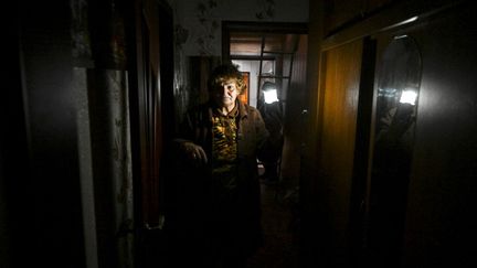 Une femme tient une lampe à l'intérieur d'une maison endommagée par un missile, à Kramatorsk, dans la région de Donetsk (Ukraine), le 12 septembre 2022. (JUAN BARRETO / AFP)