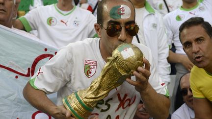 Un supporter alg&eacute;rien embrasse une r&eacute;plique de la Coupe du monde, le 26 juin 2014, &agrave; Curitiba, au Br&eacute;sil.&nbsp; (PHILIPPE DESMAZES / AFP)