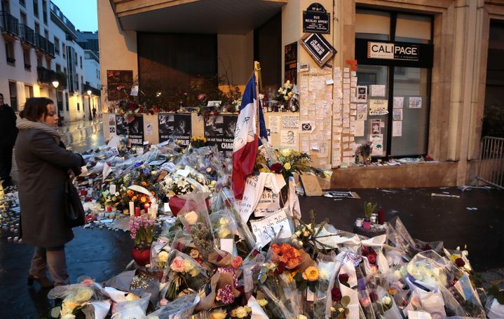 Une femme contemple les fleurs et mots déposés à l'entrée de la rue Nicolas-Appert, en hommage aux onze victimes de l'attentat du 7 janvier 2015 dans les locaux de&nbsp;"Charlie Hebdo". ((JACQUES DEMARTHON / AFP))