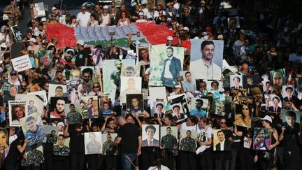 Des manifestants brandissent des drapeaux et des portraits de leurs proches disparus dans l'explosion du port de Beyrouth (Liban), le 4 août 2024. (IBRAHIM AMRO / AFP)