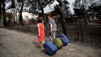 Mardi 24 juillet 2018, des&nbsp;habitants transportent leurs biens à Mati, près d'Athènes.&nbsp;Plusieurs quartiers de&nbsp;ce petit village balnéaire&nbsp;étaient encore engloutis dans une épaisse fumée blanche mardi matin.&nbsp;&nbsp; (ALKIS KONSTANTINIDIS / REUTERS)