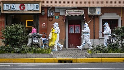 Des professionnels de la santé dans les rues de Shanghai (Chine), le 26 mars 2022. (HECTOR RETAMAL / AFP)