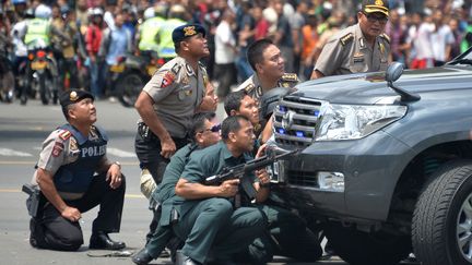 Des policiers indonésiens sont postés derrière un véhicule après une série d'attaques à Jakarta (Indonésie), le 14 janvier 2016. (BAY ISMOYO / AFP)