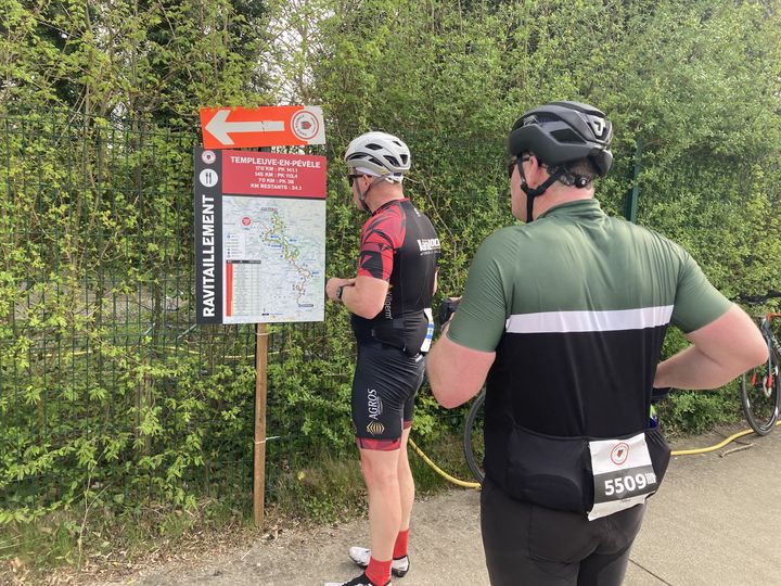 Deux cyclistes amateurs profitent du ravitaillement pour se rafraichir la mémoire sur la suite du parcours, lors de Paris Roubaix Challenge, le 6 avril 2024. (Franceinfo: sport)