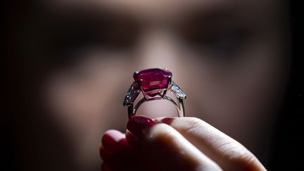 Une employ&eacute;e de Sotheby's pose avec le "Sunrise Ruby", une pierre birmane de 25,59 carats, c&eacute;d&eacute;e &agrave; Gen&egrave;ve (Suisse), mardi 12 mai, pour plus de 27 millions d'euros. (JUSTIN TALLIS / AFP)