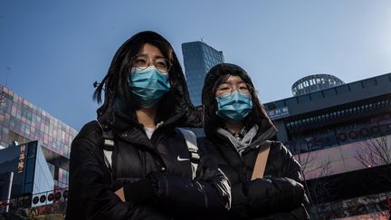 2 femmes portent un masque pour se protéger du coronavirus à Pékin (Chine), le 23 janvier 2020. (NICOLAS ASFOURI / AFP)