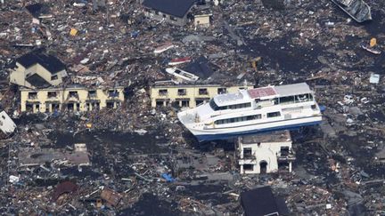 Un ferry est pos&eacute; sur une maison apr&egrave;s le passage du tsunami &agrave; Otsuchi (Japon), le 13 mars 2011. (YOMIURI / REUTERS)