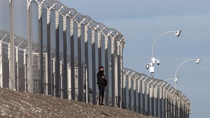 Un policier français devant une clôture le long de l'autoroute A16 près du site d'Eurotunnel, à Coquelles, près de Calais (Pas-de-Calais), le 21 janvier 2016. (PHILIPPE HUGUEN / AFP)