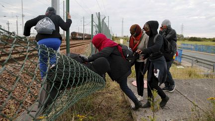 Des migrants franchissent des grillages pour tenter d'acc&eacute;der au tunnel sous la Manche, pr&egrave;s de Calais (Pas-de-Calais), le 29 juillet 2015. (PASCAL ROSSIGNOL / REUTERS)