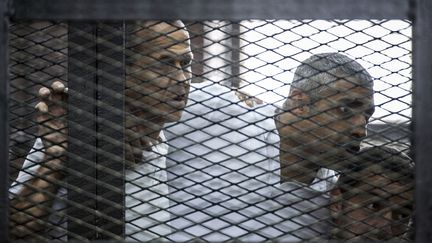 Les journalistes d'Al-Jazeera&nbsp;Peter Greste (G),&nbsp;Mohamed Fadel Fahmy (C) et&nbsp;Baher Mohamed (D), &agrave; l'&eacute;nonc&eacute; du verdict de leur proc&egrave;s, au Caire (Egypte), le 23 juin 2014. (KHALED DESOUKI / AFP)