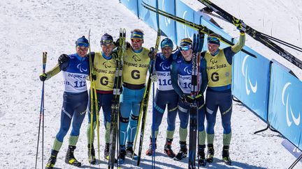 Les para biathlètes ukrainiens ont réalisé un triplé sur le sprint masculin, dans la catégorie déficient visuel. (De gauche à droite) Le médaillé d'argent Oleksandr Kazik aux côtés de son guide Serhii Kucheriavyi, le médaillé d'or Vitalii Lukianenko aux côtés de son guide Boys Babar et le médaillé de bronze Dmytro Suiarko aux côtés de son guide Oleksandr Nikonovych, posent ensemble après leur victoire, le 5 mars 2022. (THOMAS LOVELOCK / OIS / IOC / AFP)