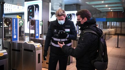 Un agent de la compagnie ferroviaire Trenord contrôle un pass sanitaire à Milan, le 6 décembre 2021. (PIERO CRUCIATTI / ANADOLU AGENCY / AFP)