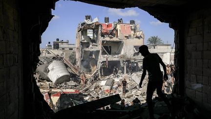 Un jeune devant le trou dans un immeuble causé par un bombardement israélien, à Khan Younès, dans le sud de la bande de Gaza, le 8 novembre 2023. (MAHMUD HAMS / AFP)