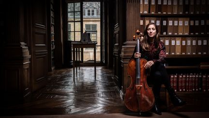 Le violoncelliste Camille Thomas joue dans la bibliiothèque de l'Insttitut de France à Paris. (MARTIN BUREAU / AFP)