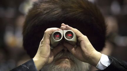 Un homme regarde &agrave; travers ses jumelles lors d'un grand rassemblement de la communaut&eacute;&nbsp;hassidique de Satmar &agrave; New York (Etats-Unis), le 23 novembre 2013. (ANDREW KELLY / REUTERS)