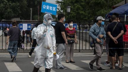 Un membre du personnel médical brandit une pancarte&nbsp;à Pékin pour aider les personnes&nbsp;à faire un test de dépistage du Covid-19, le 17 juin 2020. (NOEL CELIS / AFP)