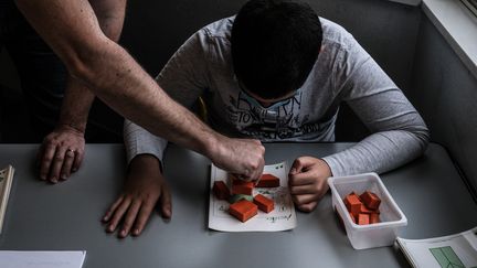 Un accompagnant des élèves en situation de handicap (AESH) avec un enfant d'une classe Ulis, dans un collège de Lyon, le 1er juin 2020. (ANTOINE MERLET / HANS LUCAS)