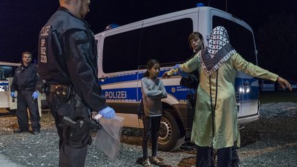 Des policers contr&ocirc;lent une femme r&eacute;fugi&eacute;e et sa fille, &agrave; la fronti&egrave;re entre l'Autriche et l'Allemagne, le 14 septembre 2015. (GUENTER SCHIFFMANN / AFP)