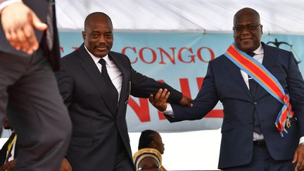 Le président&nbsp;de la RDC,&nbsp;Felix Tshisekedi, et son prédécesseur Joseph Kabila se tiennent mutuellement le bras lors de la cérémonie d'investiture&nbsp;du premier le 24 janvier 2019 à Kinshasa,&nbsp;la capitale congolaise.&nbsp;&nbsp; (TONY KARUMBA / AFP)