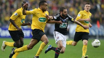 Lisandro Lopez de l'OL aux prises avec Anthony Laup et deux autres joueurs de Quevilly, le samedi 28 avril pour la finale de la Coupe de France. (THOMAS SAMSON / AFP)