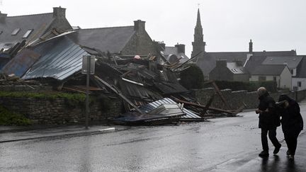 Des piétons passent devant un entrepôt détruit par la tempête Ciaran à Porspoder (Finistère), le 2 novembre 2023. (DAMIEN MEYER / AFP)