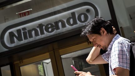 Un homme joue à "Pokémon Go" devant un magasin Nintendo, à New York (Etats-Unis), le 11 juillet 2016. (DREW ANGERER / AFP)