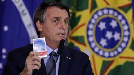 Le président brésilien, Jair Bolsonaro, présentant une boîte d'hydroxychloroquine, à Brasilia (Brésil), le 16 septembre 2020. (SERGIO LIMA / AFP)