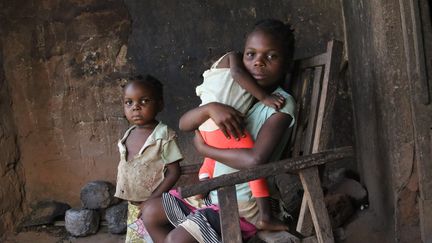 Michèle, 9 ans, tient dans ses bras sa petite sœur d'un an atteinte de malnutrition aiguë. (Save The Children)