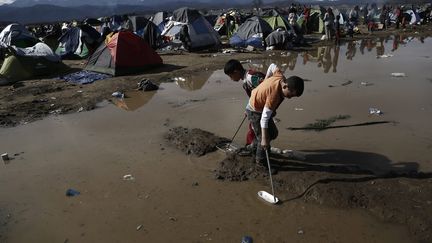 Des enfants jouent dans l'eau, le 8 mars, après la&nbsp;forte pluie qui s'est abbatue dans le poste-frontière la nuit précédente. (YANNIS KOLESIDIS / ANA-MPA)