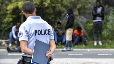 Un policier surveillant des migrants au bord de la route, près du port de Calais (Pas-de-Calais), le 16 août 2017. (PHILIPPE HUGUEN / AFP)