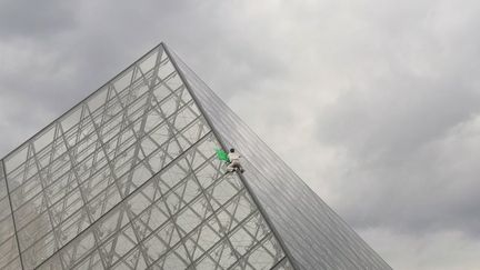 Un militant d'Extinction Rebellion grimpe sur la pyramide du Louvre (Paris), le 13 octobre 2019. (DR)