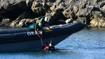 Les gardes civils espagnols&nbsp;au secours d'un migrant, après son arrivée à la nage dans l'enclave espagnole de Ceuta en provenance du Maroc voisin, le 17 mai 2021. (ANTONIO SEMPERE / AFP)