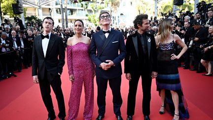 Entouré de son casting international, le réalisateur et producteur français Michel Hazanavicius laisse son regard se perdre&nbsp;vers le haut des marches avant la projection de son film "Coupez !" en ouverture du festival. De gauche à droite : l'acteur franco-britannique Finnegan Oldfield, sa compagne et actrice Bérénice Bejo, le réalisateur et producteur français Michel Hazanavicius, l'acteur français Romain Duris et l'actrice italienne Matilda Anna Ingrid Lutz. (LOIC VENANCE / AFP)