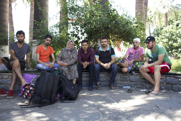 Mohamad, troisi&egrave;me &agrave; droite, patiente avec d'autres migrants syriens &agrave; l'ombre des palmiers dans un espace vert de Bodrum (Turquie), le 21 ao&ucirc;t 2015. (BENOIT ZAGDOUN / FRANCETV INFO)