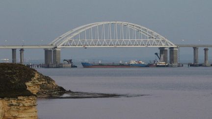 Un bateau de marchandises bloque le passage sous le pont de Crimée, devant le détroit de Kertch, qui sépare la Crimée de la Russie, le 25 novembre 2018.&nbsp; (ANDREJ KRYLOV / SPUTNIK / AFP)