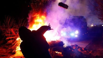 Un manifestant jette un projectil sur un véhicule, à Novi Sanjary, en Ukraine, jeudi 20 février 2020.&nbsp; (VALENTYN OGIRENKO / REUTERS)