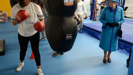 La reine Elizabeth II observe une jeune fille &agrave; l'entra&icirc;nement lors de sa visite d'une club sportif &agrave; Manchester (Royaume-Uni), le 14 novembre 2013. (NIGEL RODDIS / AFP)