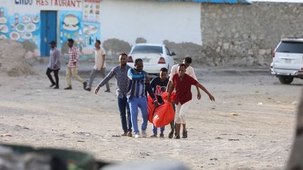 Relatives carry the body of a person killed in an attack on Lido beach in Mogadishu, Somalia, on August 3, 2024. (HASSAN ALI ELMI / AFP)