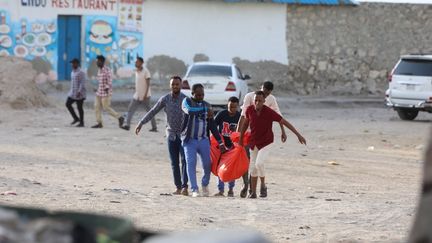 Des proches portent le corps d'une personne tuée lors d'une attaque sur la plage du Lido, à Mogadiscio (Somalie), le 3 août 2024. (HASSAN ALI ELMI / AFP)