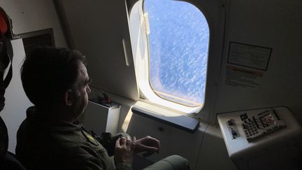 Un militaire argentin regarde à travers le hublot d'un avion américain au dessus de l'océan Atlantique, à la recherche du sous-marin, le 26 novembre 2017. (CARLOS REYES / AFP)