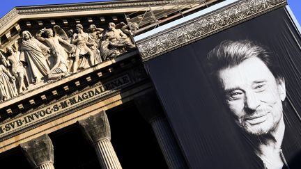 Un portrait de Johnny Hallyday, le 9 décembre 2017, devant l'église de la Madeleine à Paris, pour les funérailles du chanteur. (ERIC FEFERBERG / AFP)