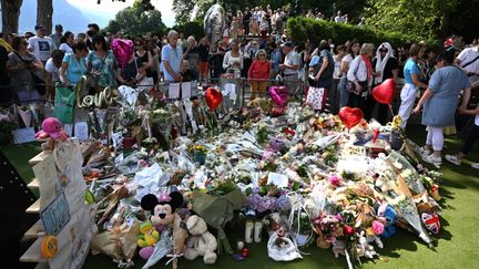 Des habitants de la ville d'Annecy (Haute-Savoie) se recueillent dans le parc où un homme a attaqué au couteau un groupe d'enfants, le 8 juin 2023, blessant six personnes. (JEAN-PHILIPPE KSIAZEK / AFP)