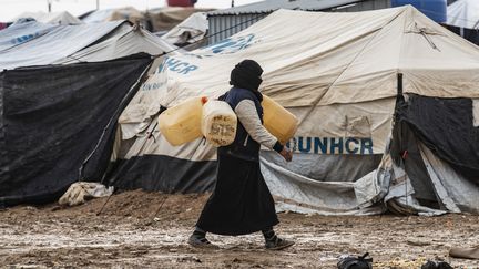 Une femme porte des jerricans, le 9 décembre 2019, dans le camp de déplacés de Al-Hol, dans le nord de la Syrie, géré par les Kurdes et où sont notamment retenus des femmes et enfants de jihadistes français. (DELIL SOULEIMAN / AFP)