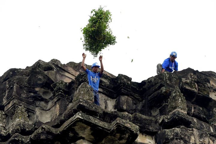 Deux jardiniers-acrobates sur les hauteurs du temple d'Angkor Wat, le 12 octobre 2020 (TANG CHHIN SOTHY / AFP)