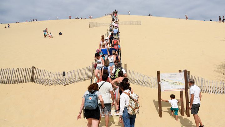 Des visiteurs prennent l'escalier pour aller au sommet de la Dune du Pilat, le 1er août 2018. (LAURENT FERRIERE / HANS LUCAS / VIA AFP)