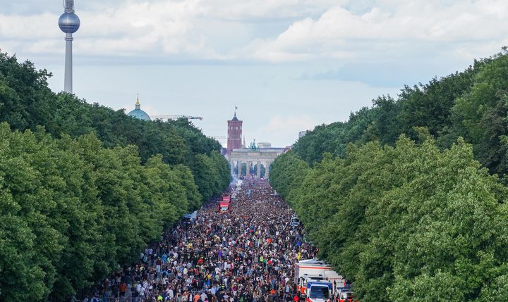 Le défilé techno "Rave The Planet" organisé par DJ Dr Motte,&nbsp;se dirige vers la porte de Brandebourg, à Berlin (Allemagne), samedi 9 juillet 2022. (JORG CARSTENSEN / DPA / AFP)