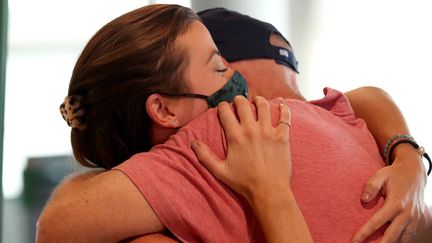 Illustration d'un hug à l'américaine avec l'artiste australienne Rebecca Underhill retrouvant son père à l'aéroport de Brisbane en Australie, le 13 décembre 2021.&nbsp; (JONO SEARLE / EPA / AAP)