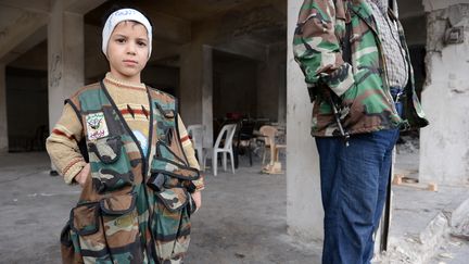 Un enfant portant une veste militaire &agrave; un chekpoint de l'Arm&eacute;e syrienne libre au nord d'Alep (Syrie), le 26 octobre 2012. (PHILIPPE DESMAZES / AFP)