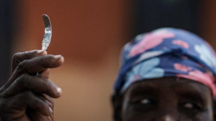 Ouganda, janvier 2018. Ancienne exciseuse ayant arrêté de pratiquer après la promulgation d'une loi interdisant les mutilations génitales féminines. Elle montre un outil de sa fabrication servant à l'excision. (YASUYOSHI CHIBA / AFP)